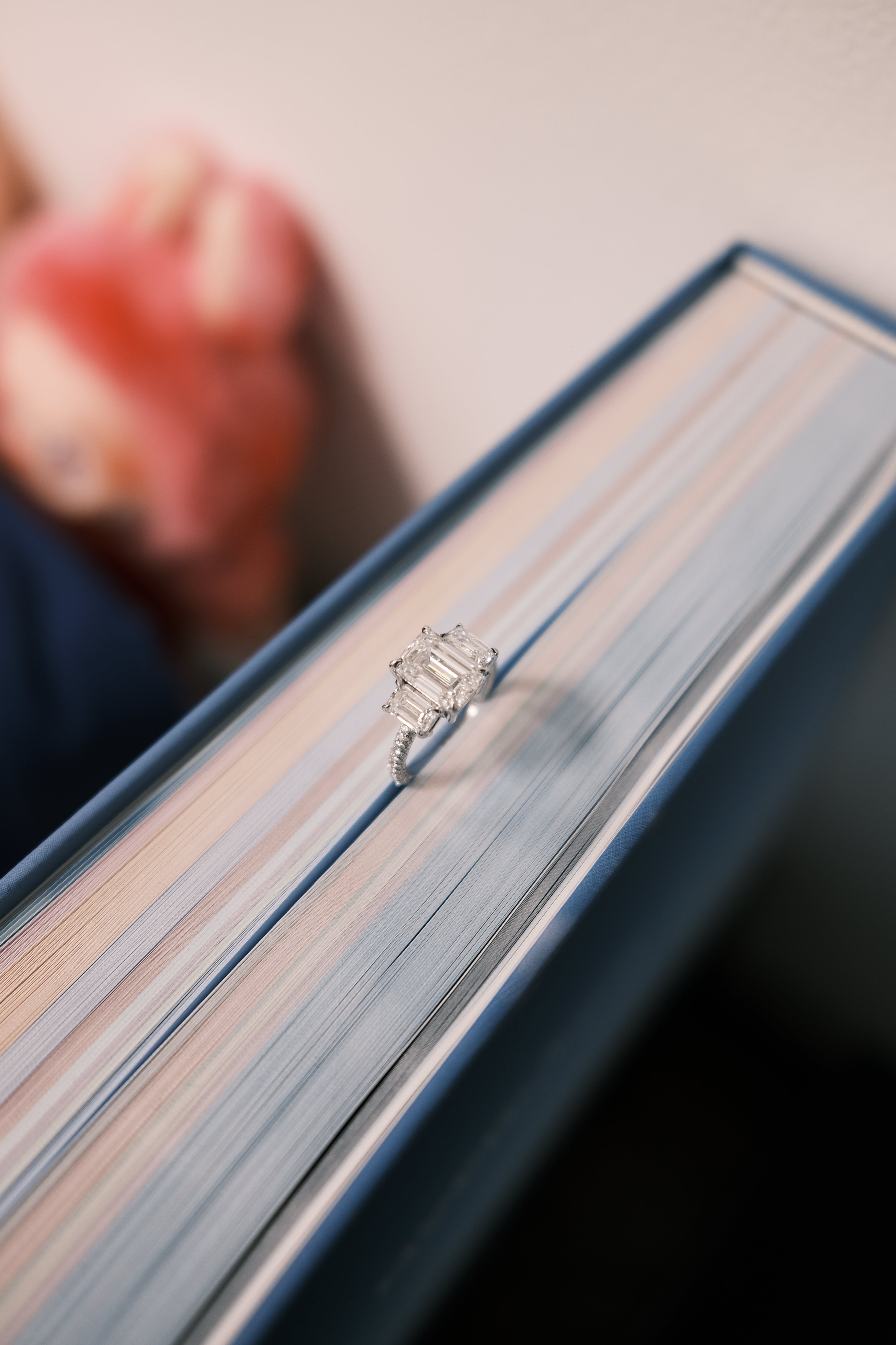 CA 3 stone emerald cut diamond ring pinned on a book
